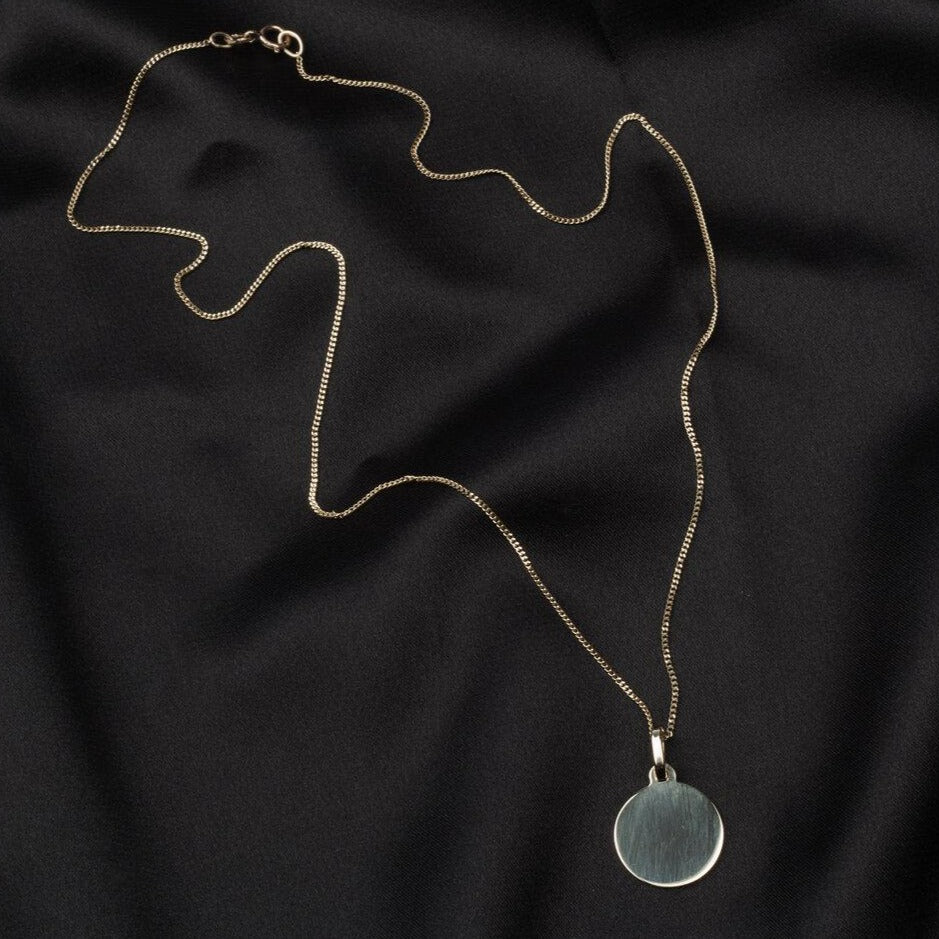 gold circle pendant on a thin curb chain
