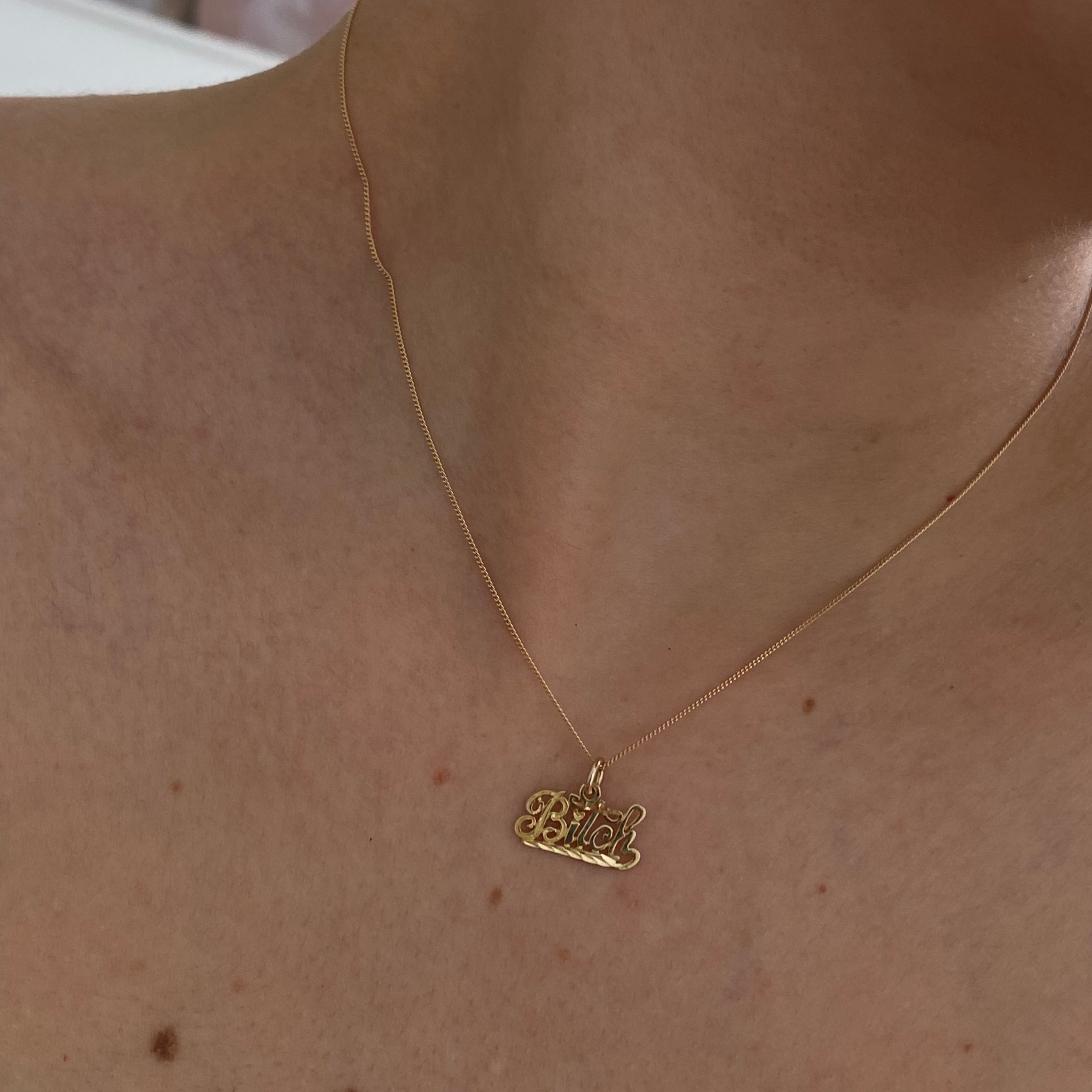 10K gold "Bitch" pendant on a thin curb chain
